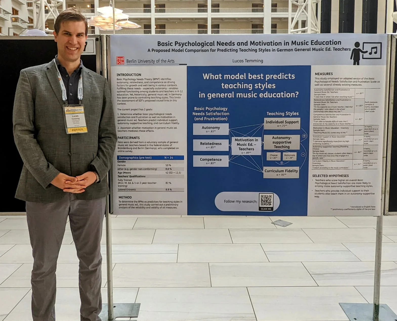 Lucas Temming steht neben einem wissenschaftlichen Poster zu Motivation und psychologischen Grundbedürfnissen